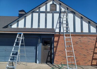 Ladders being used to paint the side of a house, with painters carefully reaching every corner.